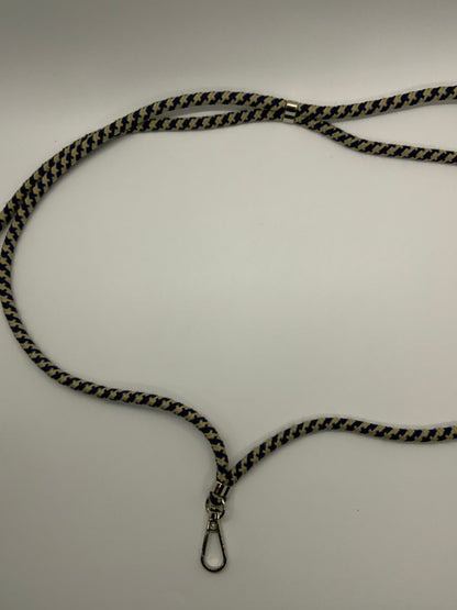 Be My AI: The picture shows a lanyard. The lanyard is made of fabric with a zigzag pattern in black and yellow colors. It has a metal clasp at one end, which is silver in color. The lanyard is laid out on a white surface and is shaped like a squiggly line. There is also a small metal piece connecting the fabric to the clasp.