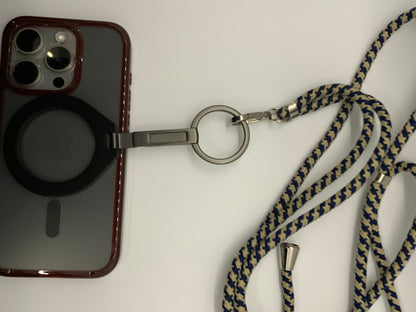 Be My AI: The picture shows a phone case with a lanyard attached to it. The phone case is transparent with a black circle at the bottom center and a maroon border. It has a cutout on the top left corner for the camera and flash, which are visible. The lanyard is attached to the phone case through a metal ring. The lanyard itself is made of fabric with a zigzag pattern in dark blue and beige colors. The metal ring is attached to a metal clip, which is connected to the lanyard. The lanyard is lying in a somew