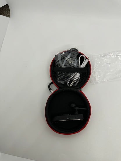 The picture shows a small, round, black case with a red zipper, which is open. The case appears to be divided into two halves. In the top half, there is a black mesh pocket containing various items including a clear plastic bag, and what looks like cables or wires. In the bottom half, there is a black device with a screen and a single earbud attached to it. The screen of the device has some text, but it's not clear enough to read in the picture. The case is placed on a white surface.