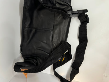 The picture shows a black bag, possibly made of leather or a similar material. The bag has a zipper on the side. There is also a black strap attached to the bag with a plastic buckle. The strap is made of a woven material and looks sturdy. The bag is placed on a white surface.