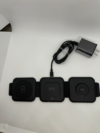 The picture shows three black square devices that are connected to each other. They are placed on a white surface. The device on the left has a power symbol on it, the one in the middle has a Bluetooth symbol, and the one on the right has a circular symbol. Above the devices, there is a black cable with a USB connector at one end and a power adapter at the other end. The power adapter is also black and has two prongs for plugging into a wall socket.