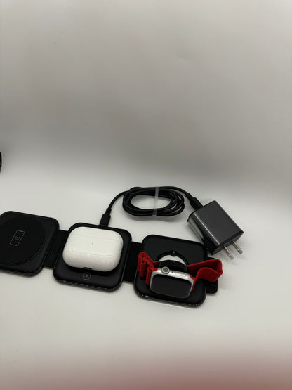 Be My AI: The picture shows several items placed on a white surface. From left to right:

1. There are three small black square cases with rounded corners. The first one has a white outline of a power button on it.

2. The second black case has a white case on top of it, which looks like a case for earbuds.

3. The third black case has a red and white smartwatch with a red band on top of it.

4. To the right of these cases, there is a black cable coiled up.

5. Next to the cable, there is a black rectangula