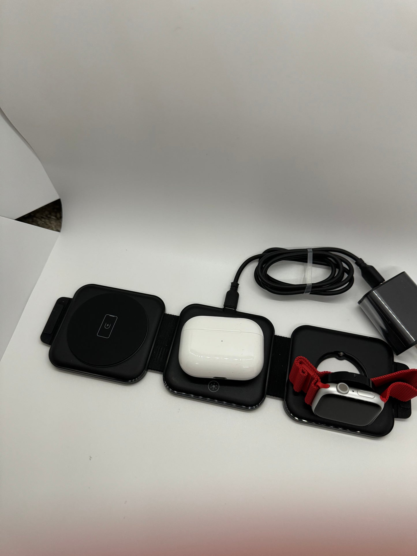 Be My AI: The picture shows a few items placed on a white surface. From left to right:

1. A square-shaped black device with rounded corners. It has a single button in the center with a power icon on it.

2. Next to it, there is another square-shaped device with rounded corners. This one is black with a white rectangular object inside it. The white object has a circular button with a power icon.

3. Next to the second device, there is a third square-shaped device with rounded corners. It is black with a red