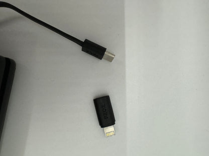 The picture shows two items on a white surface. 1. On the left side, there is a black cable with a small rectangular connector at the end. The connector has the word "Zoook" written on it. 2. On the right side, there is a small black rectangular object with a metal connector that has multiple pins. This object also has the word "Zoook" written on it. The items appear to be electronic accessories, possibly USB connectors or adapters.