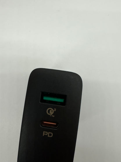 Be My AI: The picture shows a black object with a curved top against a white background. On the object, there are two ports. The top port has a green interior and the bottom port has a red interior. Between the two ports, there is a symbol that looks like a letter "Q" with a number "3" next to it, and the letters "TM" in subscript. Below the bottom port, the letters "PD" are printed.